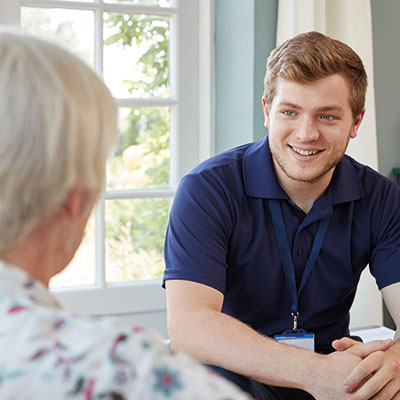 Ein Pfleger unterhält sich mit einer Seniorin